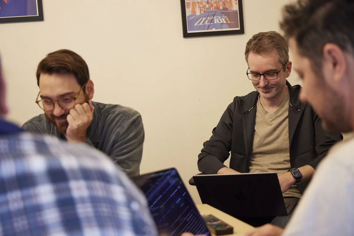 A group of colleagues looking at their laptops, coworking with each other.